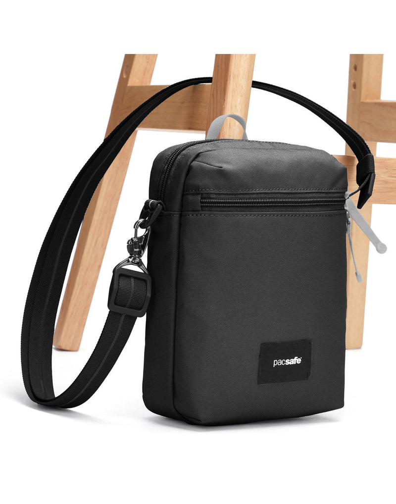 Pacsafe® GO Anti-Theft Festival Crossbody in jet black colour with shoulder strap secured to chair leg.
