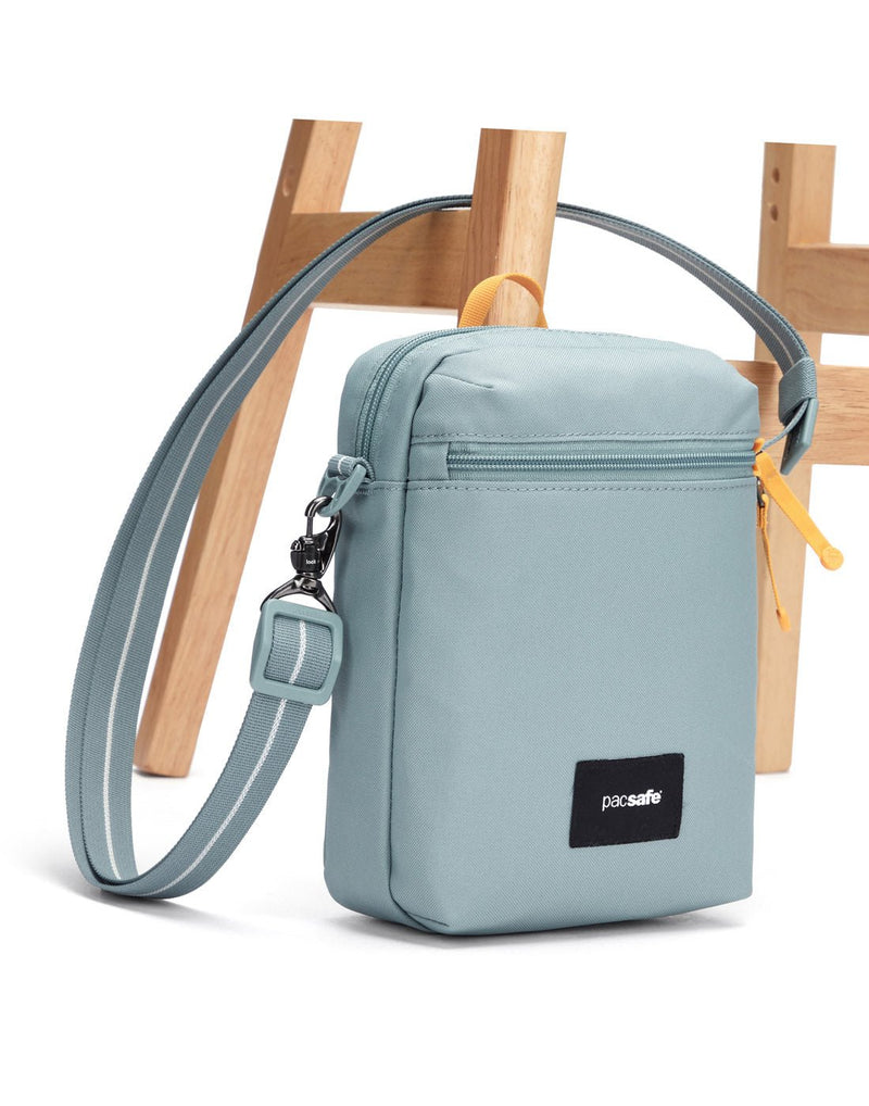 Pacsafe® GO Anti-Theft Festival Crossbody in fresh mint colour with shoulder strap secured to chair leg.
