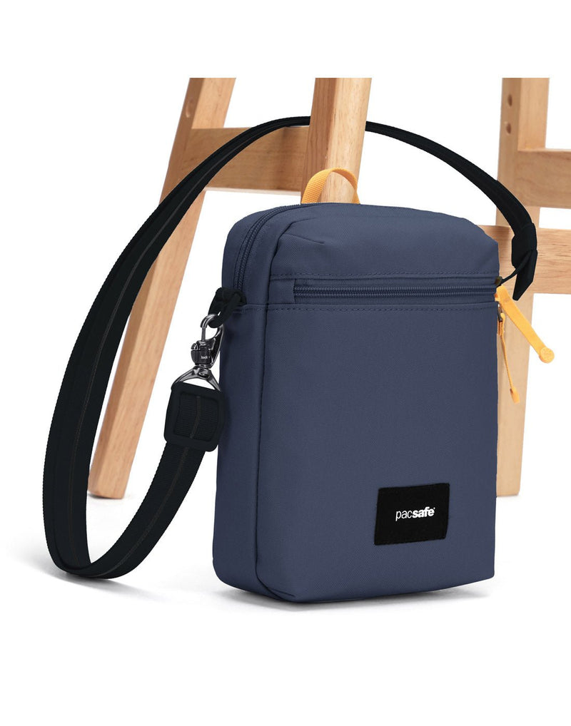 Pacsafe® GO Anti-Theft Festival Crossbody in coastal blue colour with shoulder strap secured to chair leg.
