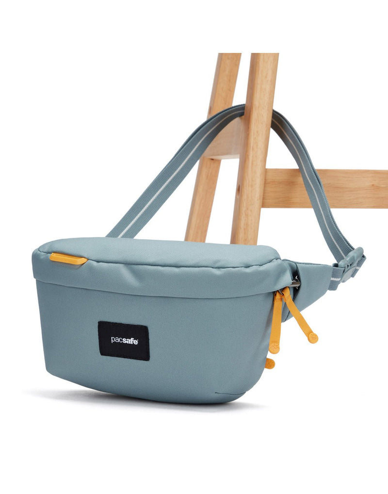 Pacsafe® GO Anti-Theft Sling Pack in fresh mint secured to a chair leg.