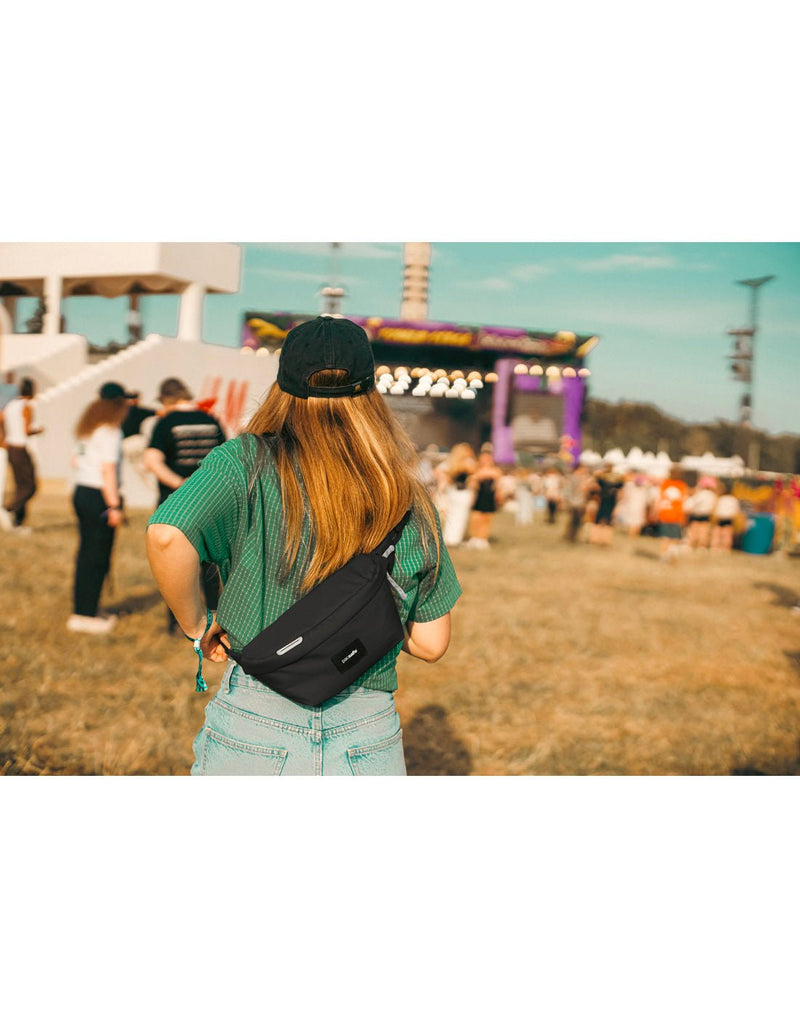 Life style image back view of a person wearing the Pacsafe® GO Anti-Theft Sling Pack in jet black colour.