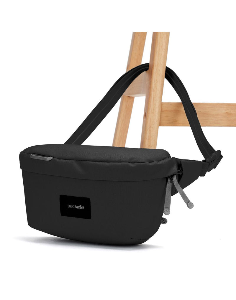 Pacsafe® GO Anti-Theft Sling Pack in jet black secured to a chair leg.