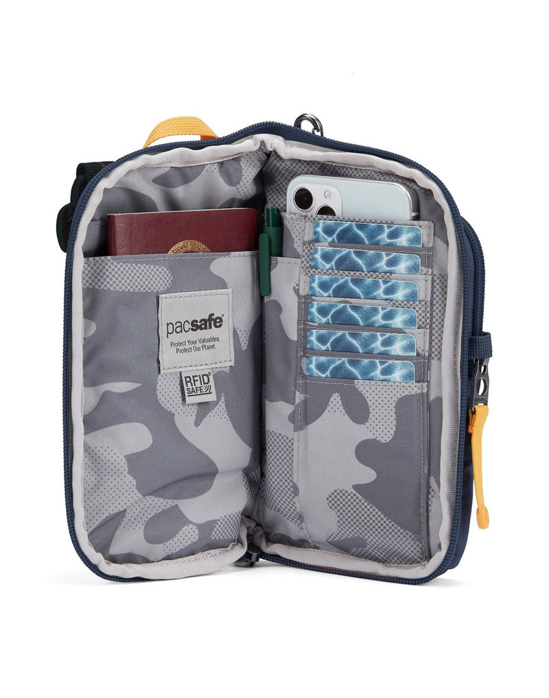 Pacsafe® GO Anti-Theft Tech Crossbody in coastal blue colour unzipped showing interior pockets that includes a RFID blocking pocket, mobile phone and credit card pockets.