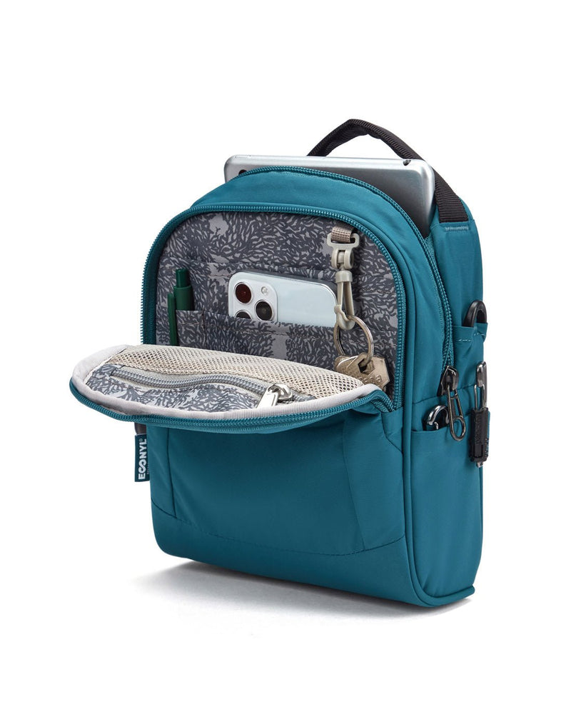 Pacsafe® LS100 Anti-theft Crossbody Bag, tidal teal, unzipped with tablet sticking out of main compartment and pen, phone and keys inside front pocket