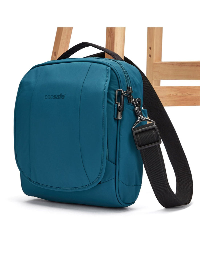 Pacsafe® LS200 Anti-theft Crossbody Bag, tidal teal, attached to chair leg with lockable strap