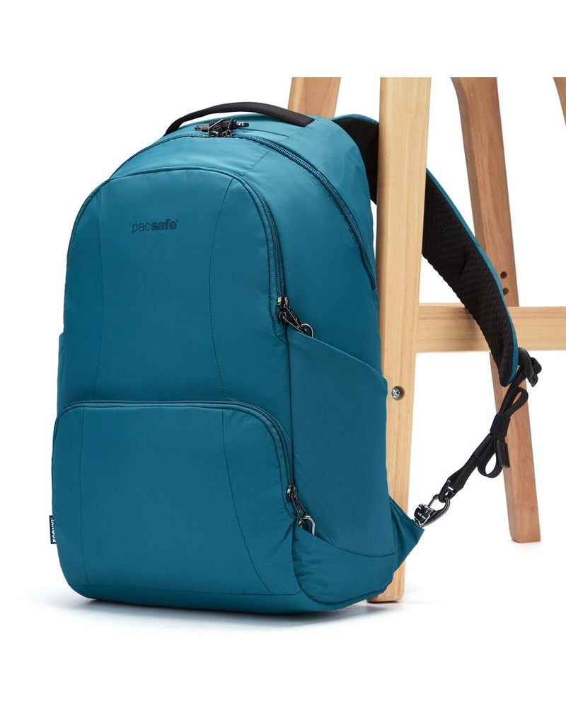 Pacsafe® LS450 Anti-Theft 25L Backpack, tidal teal, attached to a chair leg with a lockable backpack shoulder strap