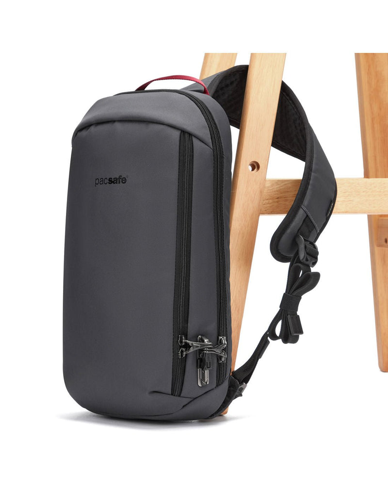 Pacsafe® Vibe 325 Anti-theft Sling Pack, slate, attached to a chair leg with lockable sling strap