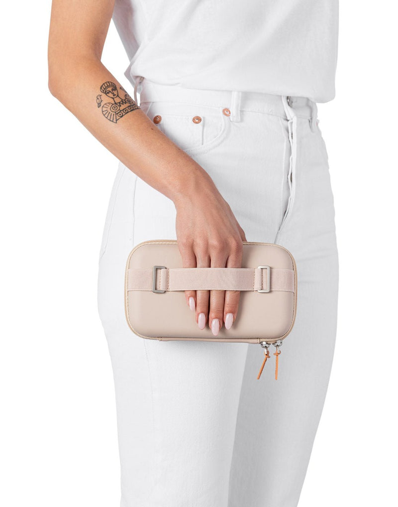Woman holding the Rollink Mini Bag Tour in Peach by the back hand strap