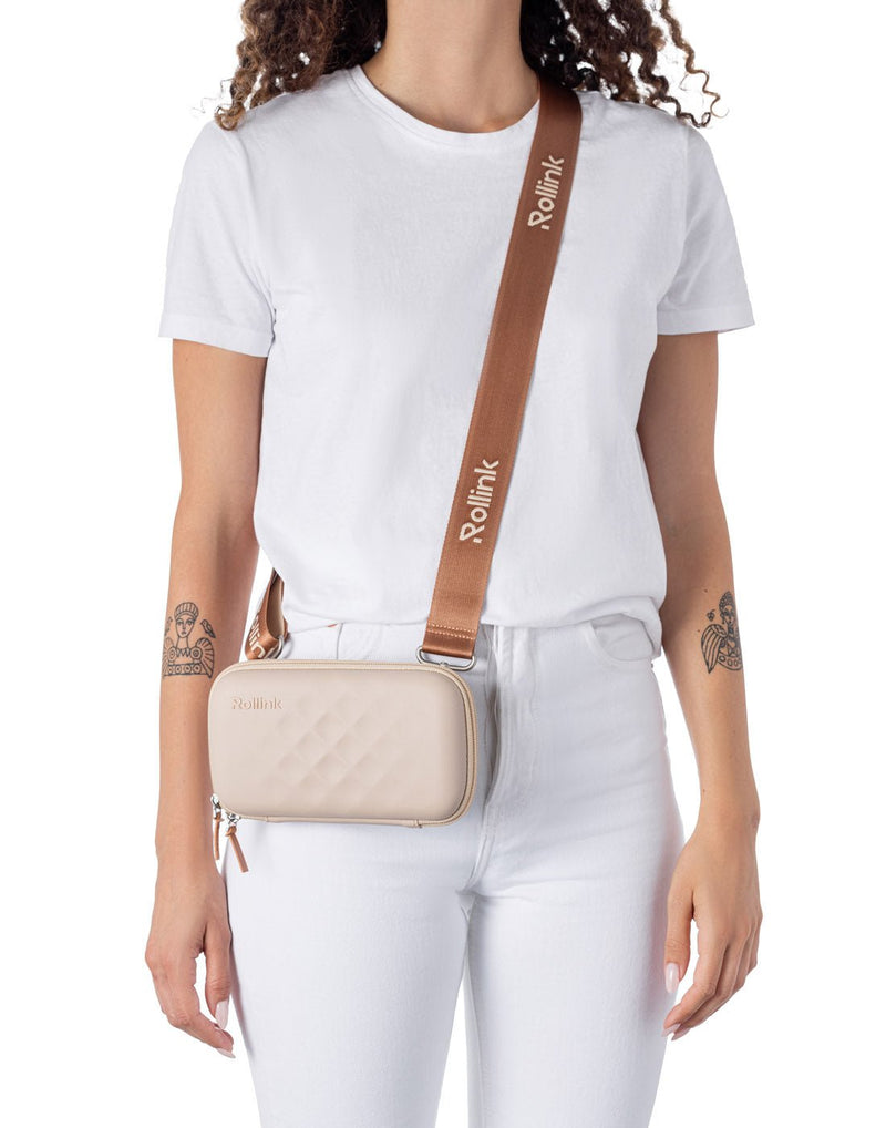 Woman wearing the Rollink Mini Bag Tour in Peach, as a cross-body with strap lengthened so bag is at hip level.