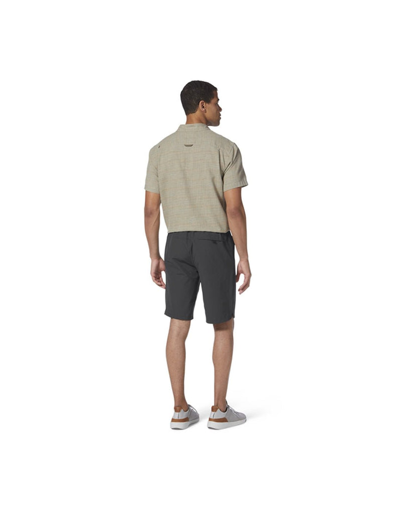 Back view of man wearing Royal Robbins Men's Backcountry Pro Multi Short in charcoal grey with beige short sleeve shirt and running shoes