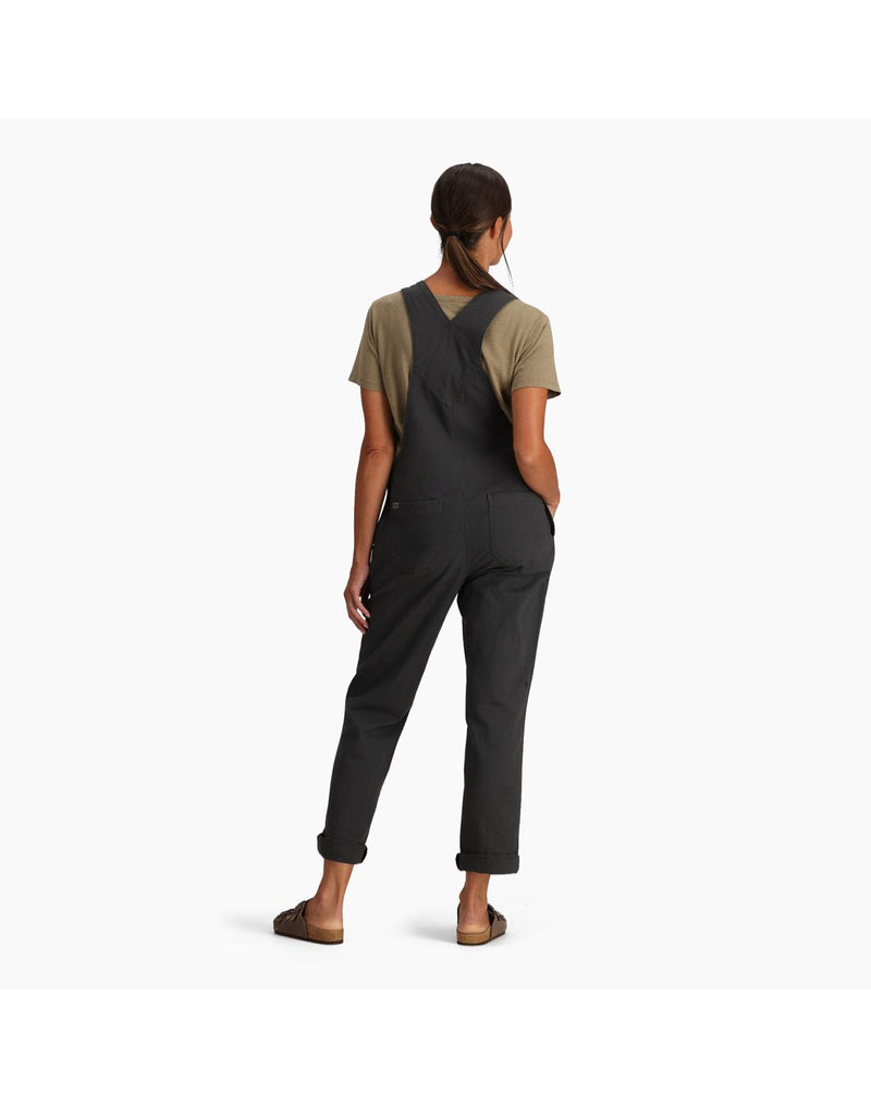 Woman wearing Royal Robbins Women's Half Dome Overall in charcoal grey over a khaki t-shirt. Bottom of pants are rolled up and she is wearing sandals, back view