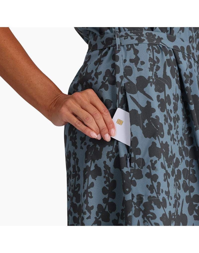 Close up of hand putting a card into pocket of the Spotless Traveller Tank Dress in Sea Alamere Print