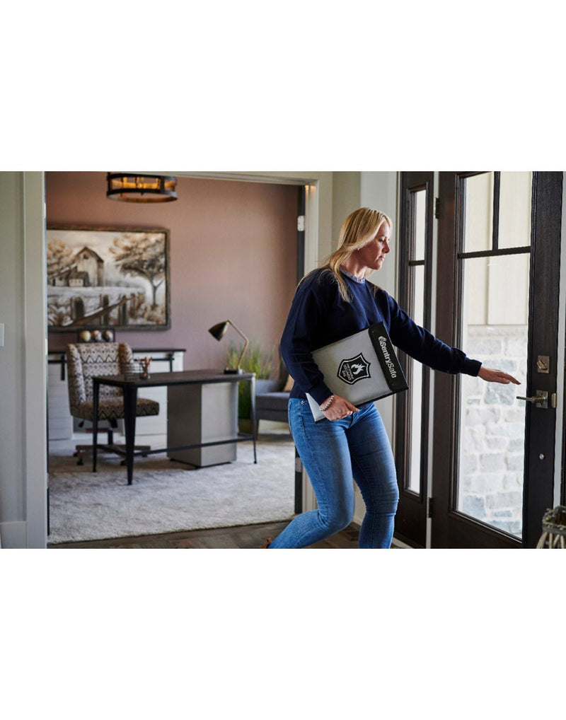 Woman holding the Sentry®Safe Fire Bag leaving outa door with an office in the background