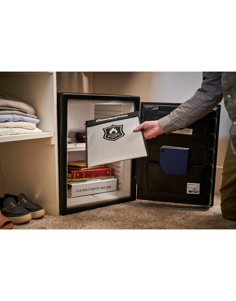 Person putting the Sentry®Safe Fire Bag into a small personal safe