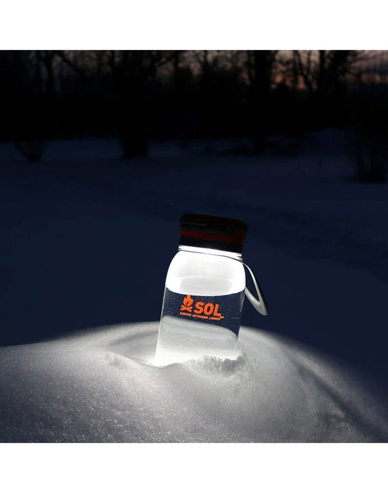 SOL Venture Solar Water Bottle Lantern lit and stuck in snowbank