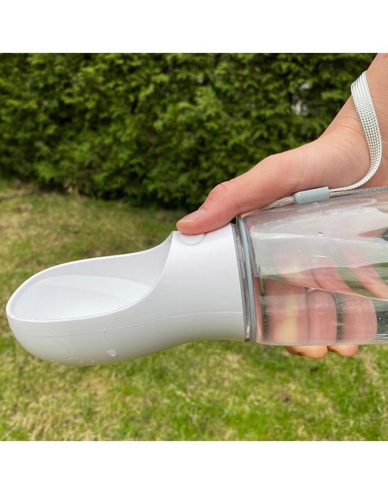 Close up image of bottle being held horizontal with thumb pressing button and showing water in the bowl part of the bottle 