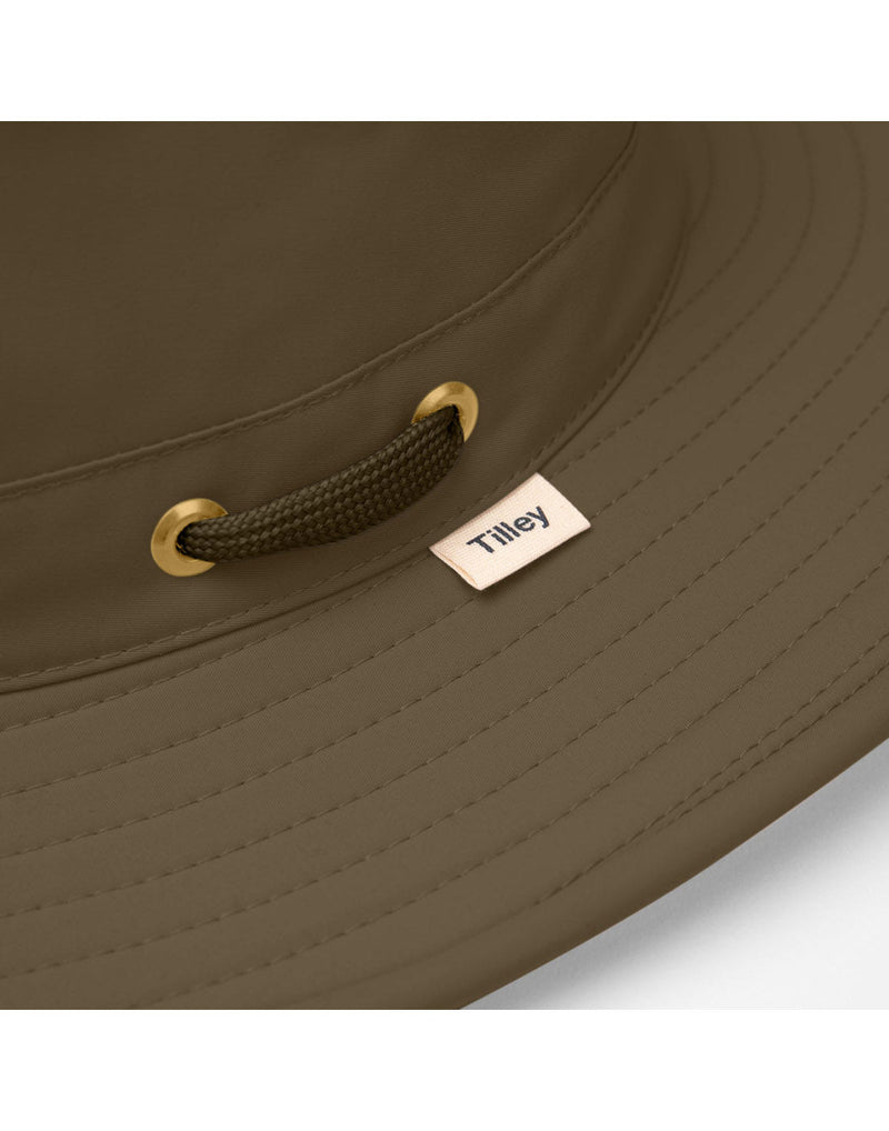 Close up of olive colour Tilley LTM6 Airflo hat side grommet and logo tag on brim