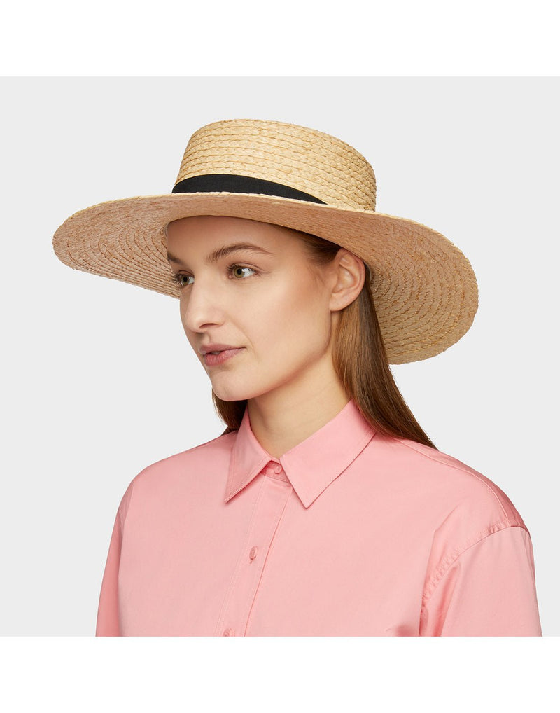 Woman wearing pink shirt and the Tilley Raffia Wide Brimmed Hat looking off to the left to show side of hat