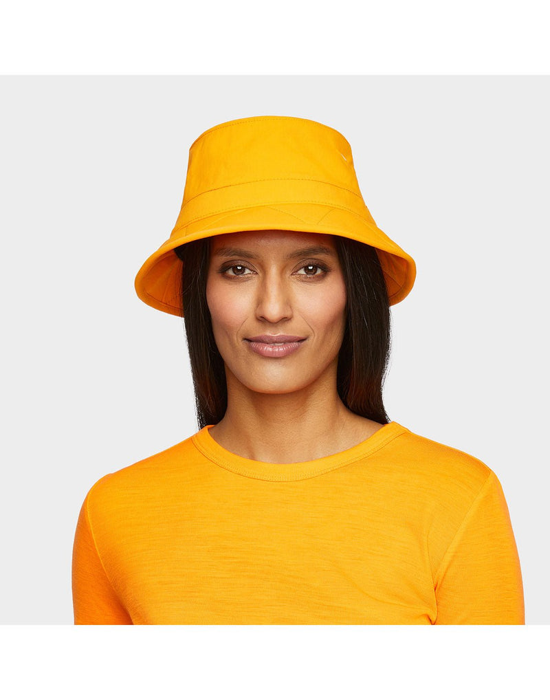 Portrait image of woman wearing Tilley Tofino Bucket Hat in bright orange with matching shirt, looking straight at camera