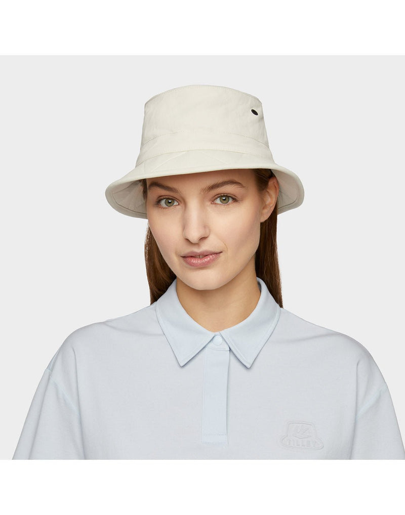 Portrait image of woman wearing light blue button shirt and Tilley Tofino Bucket Hat in stone, looking straight at camera