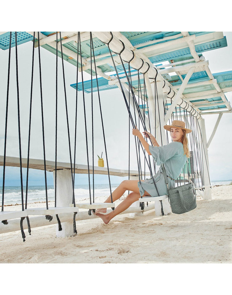 Woman outdoors on a swing, with the Travelon Boho Anti-Theft Tote in Grey Heather.